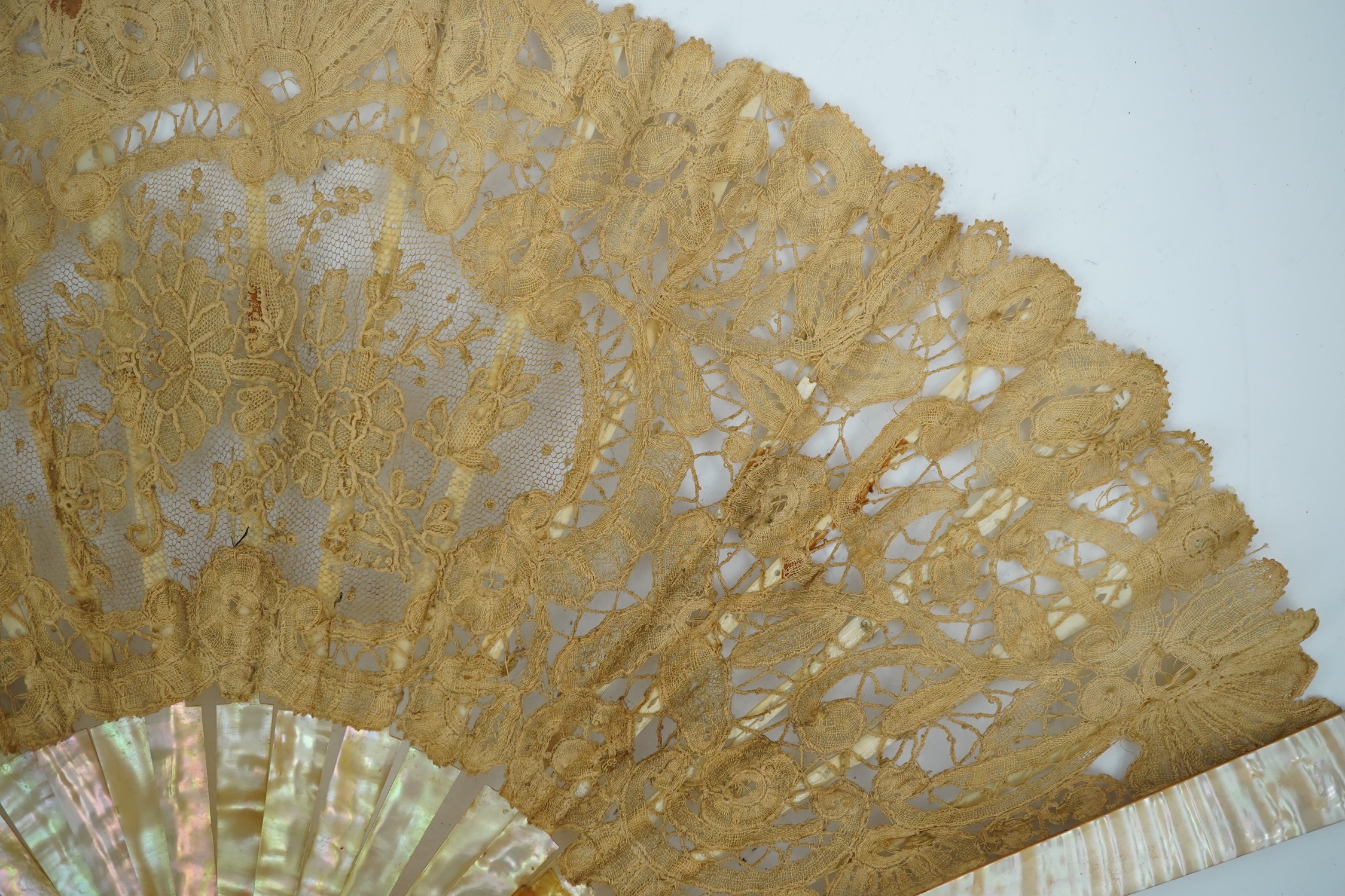 Three novelty fans with a mixed Brussels lace fan and black lace fan, a small language of love in flowers fan, a paper windmill advertising French Café fan, a carved cream Bakelite fan, a black and gilt, lace and sequin